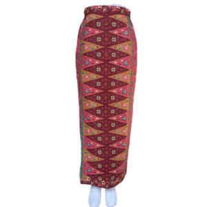 May include: A long, burgundy skirt with a pink and gold geometric pattern. The skirt has a waistband and is made of a soft, flowing fabric.