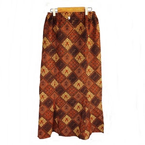 May include: A long brown skirt with a geometric pattern in shades of gold and black. The skirt has a waistband and a straight silhouette.
