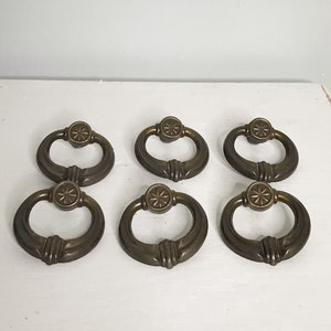 以下が含まれることがあります： 星形のデザインの中央にリングプルと星形のデザインが施された、アンティークブラスのキャビネットノブ6個。