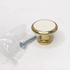 May include: A gold cabinet knob with a white ceramic top. The knob comes with a silver screw.