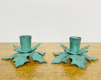 May include: A pair of teal green metal candle holders shaped like leaves.
