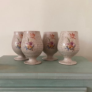 Peut inclure: Quatre verres en céramique blanche avec des motifs floraux et un glaçage moucheté. Les verres ont une base arrondie et un large bol.