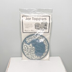 May include: A package of blue and white jar toppers. Each package includes 6 jar covers, 6 rounds of crocheted lace, and a generous 22' of yarn per topper. The package is labeled "Jar Toppers" and "Potpourri Press".