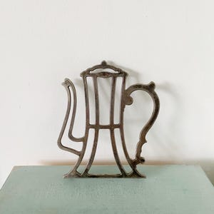 Peut inclure: Sous-plat en métal argenté en forme de théière. Le sous-plat est une découpe avec une poignée décorative.