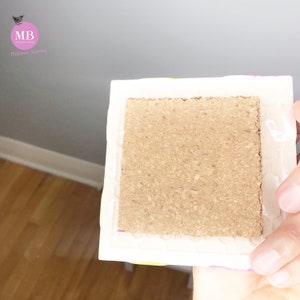 May include: A close-up of the back of a square picture frame with a cork backing. The frame is white with a colorful pattern on the edges.