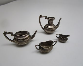 May include: A miniature silver tea set with a teapot, creamer, and sugar bowl. The set is made of silver and has a traditional design.