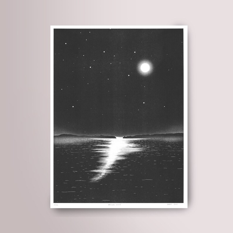 May include: Monochrome print of a moonlit seascape. The artwork shows a bright full moon and stars in the night sky, reflected on the water's surface. The print has a minimalist style, with the artist's signature at the bottom.