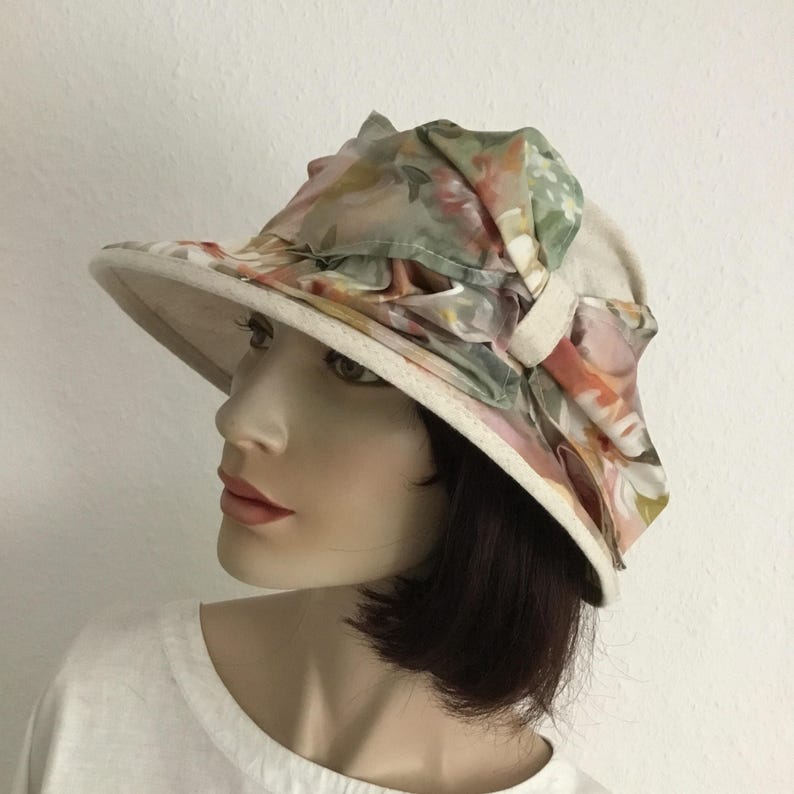 May include: A white ceramic mug with a black handle and the text "But First, Coffee" in a bold, black font. The mug is set against a blurred background, suggesting a cozy setting.