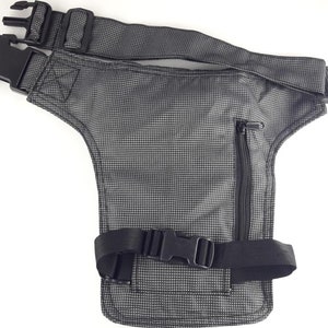 Puede incluir: Una ri&ntilde;onera negra y gris con un bolsillo con cremallera y correas ajustables. La ri&ntilde;onera est&aacute; hecha de un tejido texturizado y tiene una peque&ntilde;a hebilla negra.
