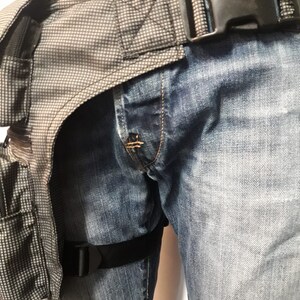 Puede incluir: Una correa de pierna t&aacute;ctica negra con una bolsa t&aacute;ctica gris y negra unida a ella. La correa se lleva sobre un par de pantalones vaqueros azules.
