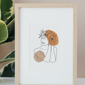 May include: A framed print of a line drawing of a person with flowers in their hair. The drawing is in black and white, and the background is a light brown color.