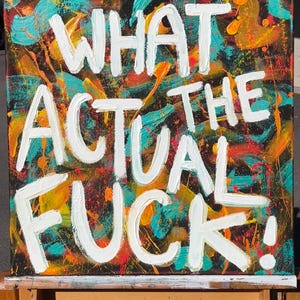 Könnte beinhalten: Abstraktes Gemälde mit dem Schriftzug "WHAT THE ACTUAL FUCK!" in weißen Buchstaben. Der Hintergrund zeigt bunte Spritzer aus Türkis, Orange, Gelb und Rot auf schwarzem Hintergrund.