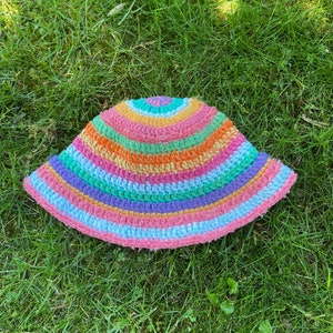 May include: A multi-colored crocheted bucket hat with stripes of pink, orange, yellow, green, blue, and purple.