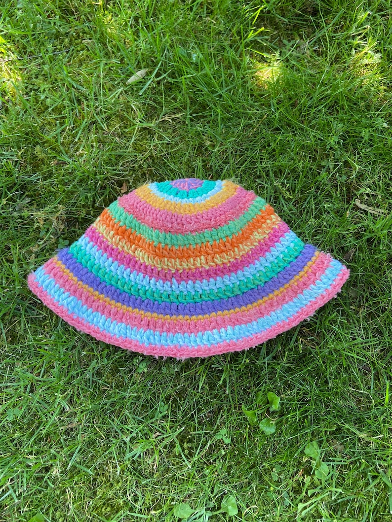 May include: A multi-colored crocheted bucket hat with stripes of pink, orange, yellow, green, blue, and purple.