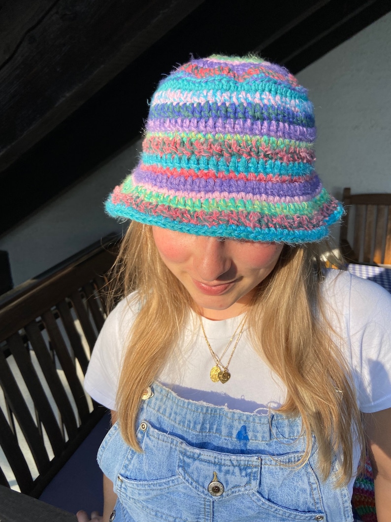 May include: A colorful crocheted bucket hat with stripes of pink, blue, green, and purple.
