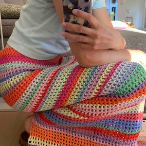 K&ouml;nnte beinhalten: Ein bunter H&auml;kelrock mit einem regenbogenfarbenen Streifenmuster. Der Rock ist aus einem leichten, atmungsaktiven Material gefertigt und hat eine lockere, flie&szlig;ende Passform.