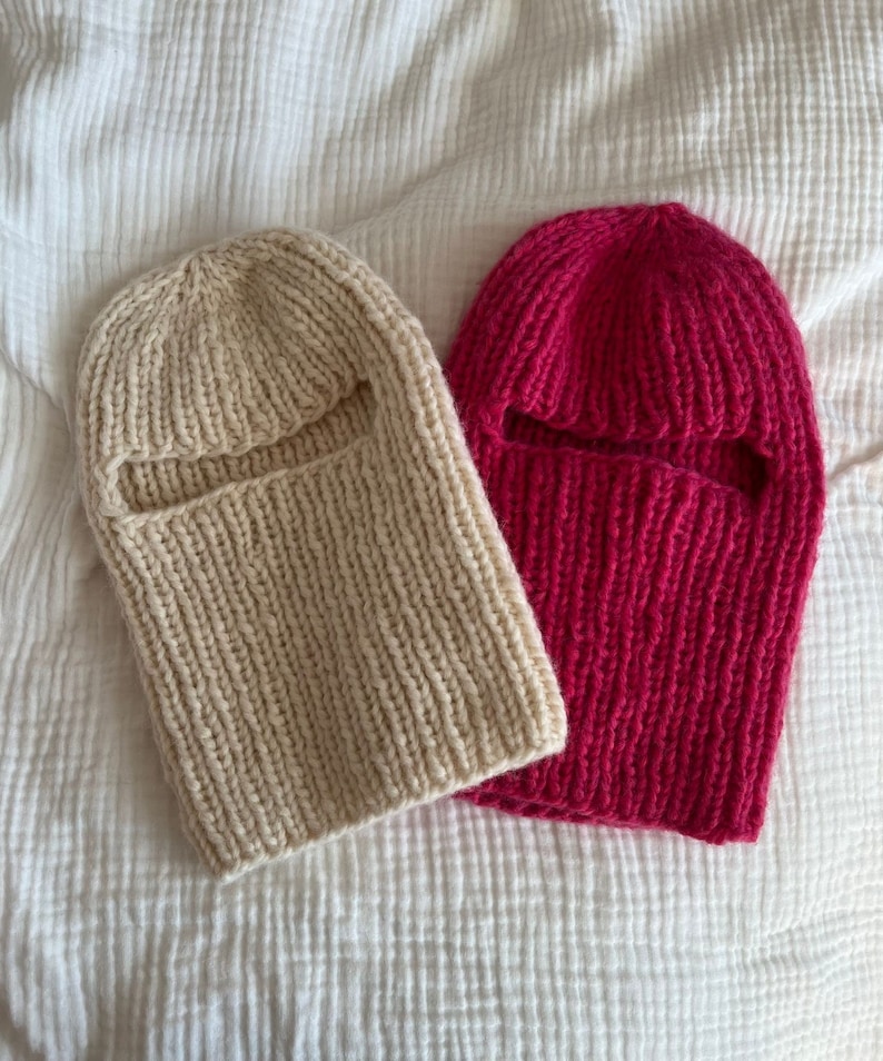 May include: Two knitted balaclavas, one beige and one pink, with eye holes.