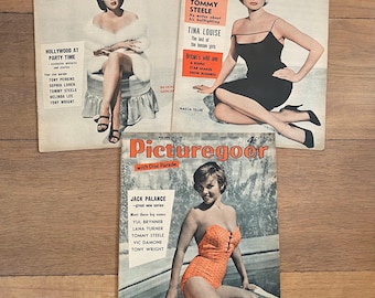 May include: Three vintage "Picturegoer" magazines. The covers feature glamorous women in various poses. The magazines have text and headlines, including "Hollywood at Party Time" and "Tommy Steele". The magazines are on a wooden surface.