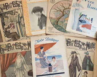 Op de afbeelding: Een verzameling vintage modebladen met kleurrijke covers. De tijdschriften tonen illustraties van vrouwen in verschillende outfits, met titels als "Mode Illustrée" en "Le Petit Echo de la Mode". De tijdschriften zijn gerangschikt op een houten oppervlak.