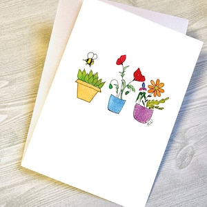 May include: A greeting card with a hand-drawn illustration of four potted plants. The plants are a succulent, a red poppy, a purple flower, and a yellow flower. A bee is flying above the succulent. The card is signed "RW".