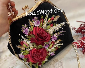 May include: Black velvet handbag with a gold chain strap and handle. The bag is decorated with red rose and floral embroidery, with the text "Naz'sWardrobe" on the front. The bag has a gold clasp and trim.