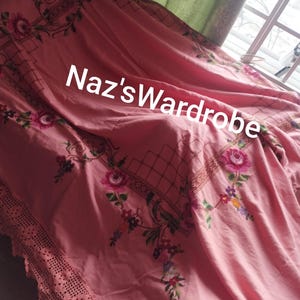 May include: Pink floral bedspread with embroidered roses and a crocheted lace edge. The bedspread features the text "Naz's Wardrobe" in white. The design includes a grid pattern and floral accents.
