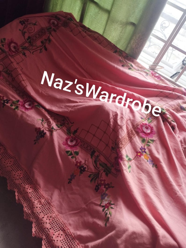 May include: Pink floral bedspread with embroidered roses and a crocheted lace edge. The bedspread features the text "Naz's Wardrobe" in white. The design includes a grid pattern and floral accents.