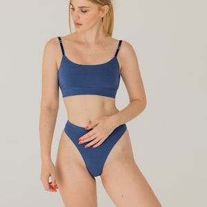 Puede incluir: Conjunto de dos piezas de ropa interior azul. La parte superior es un top corto con tirantes finos y cuello redondo. La parte inferior es de cintura alta. El conjunto está hecho de un material suave y cómodo.