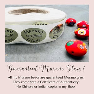 May include: A roll of stickers with the text "Murano certificate Glass" on them. The stickers are gold with black text. There are also several colorful Murano glass beads in the image.