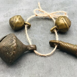 K&ouml;nnte beinhalten: Ein Satz von vier antiken Messingglocken, die mit einer Schnur zusammengebunden sind. Die Glocken haben unterschiedliche Formen und Gr&ouml;&szlig;en, einige haben komplizierte Designs.