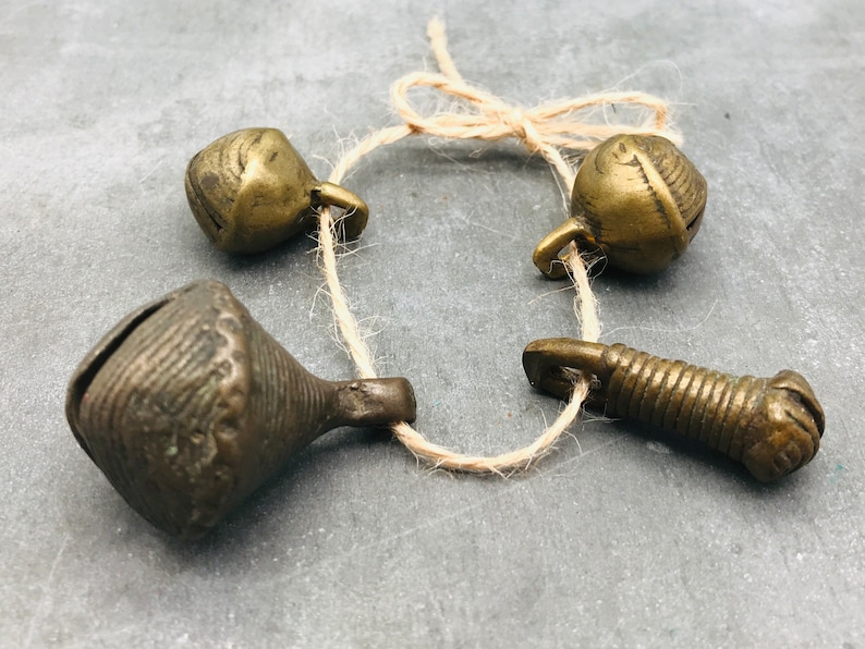 K&ouml;nnte beinhalten: Ein Satz von vier antiken Messingglocken, die mit einer Schnur zusammengebunden sind. Die Glocken haben unterschiedliche Formen und Gr&ouml;&szlig;en, einige haben komplizierte Designs.