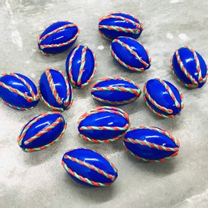Op de afbeelding: Een verzameling van twaalf blauwe, ovale kralen met witte en oranje randen. De kralen zijn gerangschikt op een grijs oppervlak.