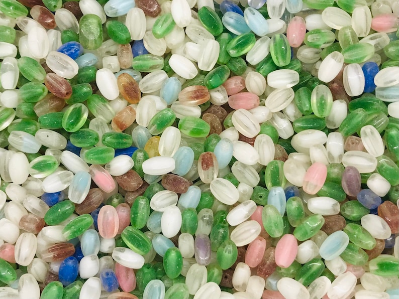 Pu&ograve; includere: Una collezione di perline di vetro ovali in vari colori, tra cui bianco, verde, blu e rosa. Le perline hanno un aspetto traslucido e smerigliato.