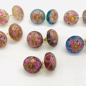May include: Assortment of colorful glass earrings with gold accents and pink, blue, and white floral patterns.