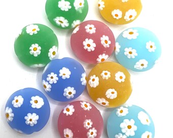 May include: Assortment of ten round, colorful glass beads with a white daisy pattern. The beads are in shades of green, blue, yellow, pink, and light blue.