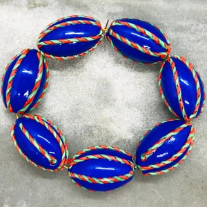 Op de afbeelding: Een blauwe en witte ovale kralenketting met een gouden sluiting. De kralen zijn versierd met rode en groene strepen.
