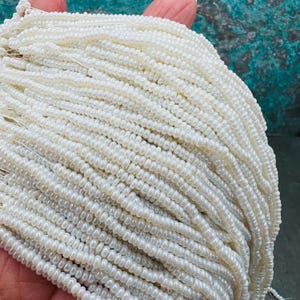 May include: A large strand of white seed beads, perfect for jewelry making or crafting.