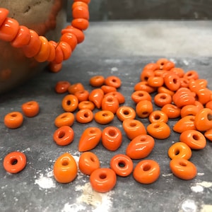Puede incluir: Un montón grande de cuentas de cerámica naranja, algunas son redondas y otras ovaladas.