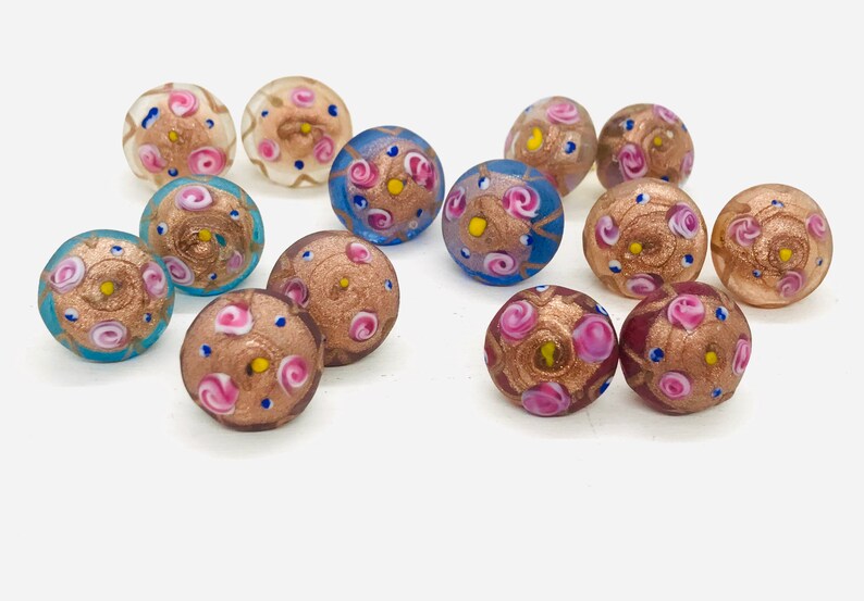 May include: Assortment of colorful glass beads with intricate floral patterns and gold accents. The beads are round and have a glossy finish.
