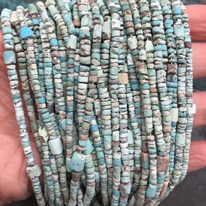 K&ouml;nnte beinhalten: Eine Str&auml;hne aus T&uuml;rkisperlen mit einem Mix aus hell- und dunkelblauen T&ouml;nen und einer rauen, unregelm&auml;&szlig;igen Textur. Die Perlen sind klein und gleichm&auml;&szlig;ig gro&szlig; und auf einer durchsichtigen Schnur aufgef&auml;delt.