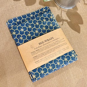 Peut inclure: Un lot d'emballages alimentaires réutilisables avec un motif géométrique bleu et doré. L'emballage est accompagné d'une étiquette en papier brun avec du texte en français. Idéal pour conserver les aliments.