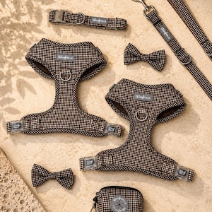 May include: A pet accessory set featuring a brown and black houndstooth pattern. The collection includes two harnesses with metal D-rings and plastic buckles, a collar, a lead with a metal clip, two bow ties, and a small zipped pouch with a logo.