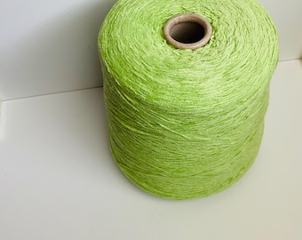 May include: A large spool of bright green yarn. The yarn is tightly wound around a cardboard core, creating a cylindrical shape. The vibrant color and texture suggest it's suitable for various crafting projects, such as knitting or crochet.