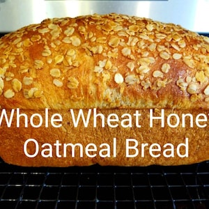 May include: A loaf of whole wheat honey oatmeal bread with a golden brown crust and a topping of rolled oats.