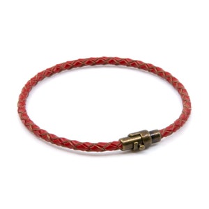 May include: A red braided leather bracelet with a brass magnetic clasp.