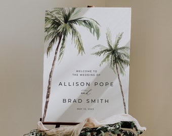 May include: A white wedding welcome sign with a watercolor illustration of palm trees. The sign reads "Welcome to the wedding of Allison Pope and Brad Smith, May 12, 2023".