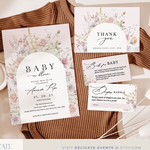May include: A floral baby shower invitation with a watercolour design. The invitation features a floral arch with the text "Baby in Bloom" and the date "05.20.23".