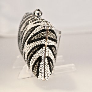 May include: A black and white zebra-print clutch purse covered in rhinestones.