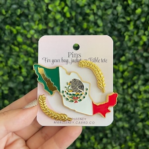 May include: A gold-toned metal enamel pin shaped like the map of Mexico, featuring the national flag colors of green, white, and red with the central eagle emblem. Two separate gold-toned wheat stalk pins accompany it on a white display card.