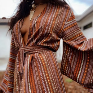 Puede incluir: Un vestido de envoltura marr&oacute;n y naranja con estampado geom&eacute;trico, cuello en V profundo y mangas largas. El vestido tiene un cintur&oacute;n de lazo en la cintura.